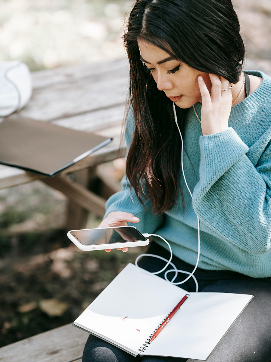 Dame zit met pen schrift op schoot en controleert oh haar pdf toegankelijk is, op een telefoon