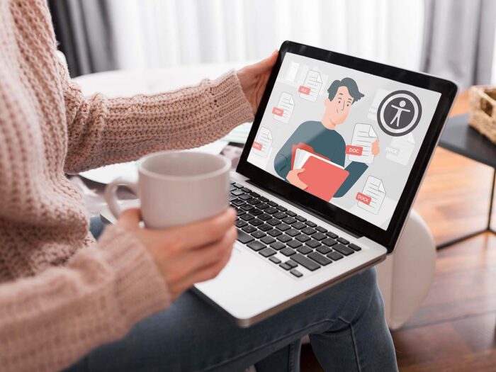 Vrouw met in haar hand een kop koffie en op schoot een laptop. Hierop een tekening van een man met een document in zijn hand en het accessibility-logo en een digitaal toegankelijke pdf.