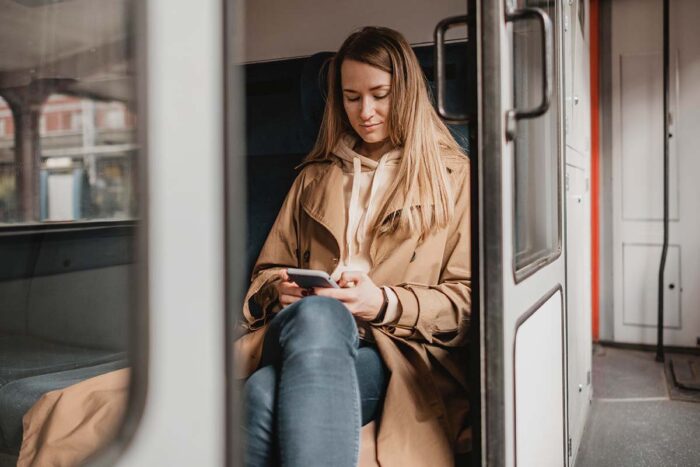 Vrouw zit een trein en luistert naar een toegankelijke pdf op haar smartphone 